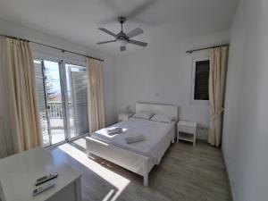 a white bedroom with a bed and a large window at Coral Blue Bay Villa in Coral Bay