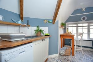 een keuken met blauwe muren, een wastafel en een tafel bij The Roost in Budleigh Salterton