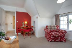 un soggiorno con una sedia rossa e un tavolo di The Roost a Budleigh Salterton Altre 21 foto