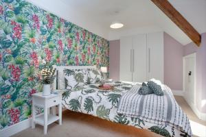 una camera da letto con un letto e carta da parati tropicale di The Roost a Budleigh Salterton