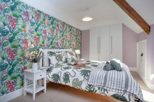 a bedroom with a bed with a tropical wallpaper at The Roost in Budleigh Salterton