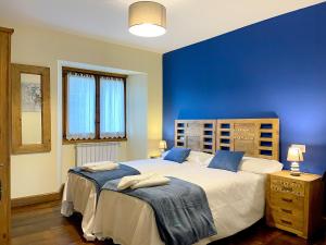 a bedroom with two beds and a blue wall at CASA RURAL ERVITENA in Oteiza
