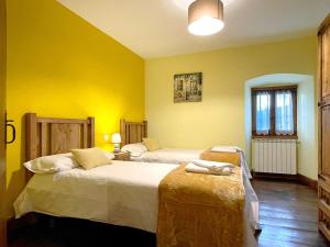 two beds in a room with yellow walls at CASA RURAL ERVITENA in Oteiza +6 photos