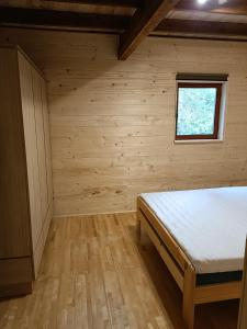 1 dormitorio con 1 cama en una habitación de madera en Dom Sosnowy, en Szczytno