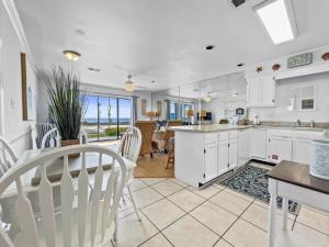 a kitchen with white cabinets and a table and chairs at Emerald Shores #1001 Condo in Panama City Beach