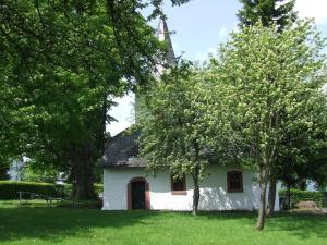 een klein wit huis met bomen in het gras bij Gästehaus Jütten in Hellenthal