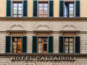 um edifício com janelas com persianas verdes e um calendário de hotéis em FH55 Hotel Calzaiuoli em Florença