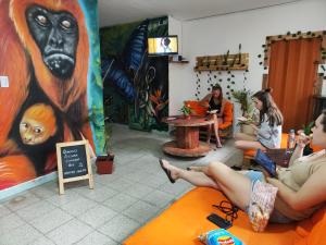 um grupo de pessoas sentadas numa sala com uma pintura de macaco em Serrania Hostal em Medellín