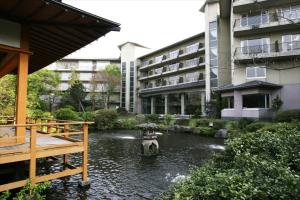 a fountain in a pond in front of a building at Yufuin Kotobuki Hananosho in Yufuin