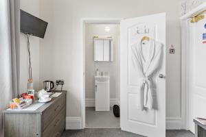 a bathroom with a robe hanging on a door at Cherwood Guest House in Paignton +130 photos