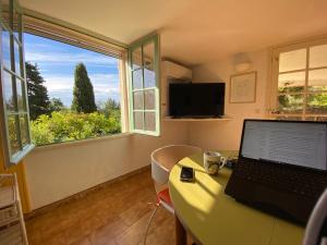 einen Laptop auf einem Schreibtisch in einem Zimmer mit Fenster in der Unterkunft Villa Lou Gecko in Hyères