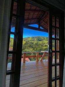 an open door to a deck with a mountain view at Chalé Som do Riacho com Hidromassagem e Lareira á 20 minutos de Gonçalves mg in Gonçalves