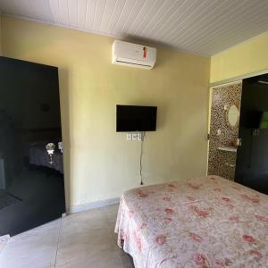 a bedroom with a bed and a tv on the wall at Pousada Casa Ferreira in Pirenópolis