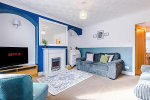 ein Wohnzimmer mit einem TV, einem Sofa und einem Kamin in der Unterkunft Prenton House in Chester