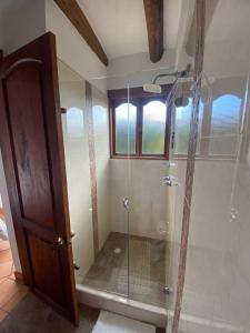 a shower with a glass door in a bathroom at Hostal Villa Anita in Villa de Leyva