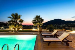 a swimming pool with two lounge chairs and palm trees at Lavish Athens Pool Villa - Indulge in Luxury in Anavyssos