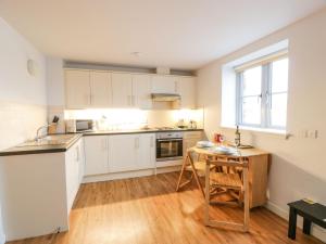 a kitchen with white cabinets and a wooden table at Tides Reach in Newton Stewart