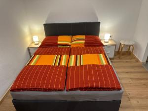 Elle comprend un grand lit avec des draps colorés et 2 tables. dans l'établissement Ferienwohnung Wohlfahrter, à Bad Mitterndorf