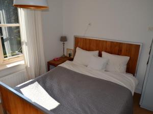 een slaapkamer met een bed met een houten hoofdeinde en een raam bij Duinappartementen Schoorl in Schoorl