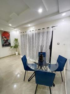 a dining room with a glass table and blue chairs at Room in Apartment - Grande Chambre Avec Toilette Integrees in Dakar