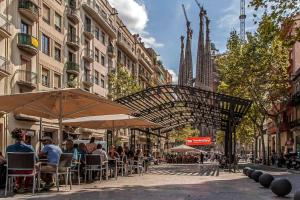 a group of people sitting under umbrellas on a city street at Habitat Apartments Sweet Sagrada Familia in Barcelona