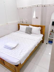 uma cama com lençóis brancos e almofadas brancas em Hotel thanh vinh em Ho Chi Minh