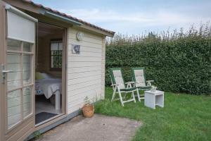 une petite maison avec deux chaises et une table dans la cour dans l'établissement Oud Drimmelen, à Drimmelen