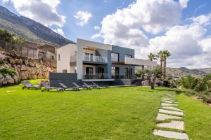 uma casa com um jardim verde com bancos em Villa vista mare Piscina e SPA em Castellammare del Golfo