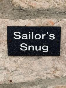 a sign on a stone wall that says sailors sing at Sailors Snug in Beadnell