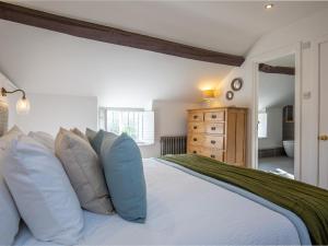 a bedroom with a large white bed with pillows at Sage Cottage in Blockley