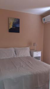 1 dormitorio con 1 cama blanca grande y mesita de noche en Departamento en el centro de Mendoza en Mendoza