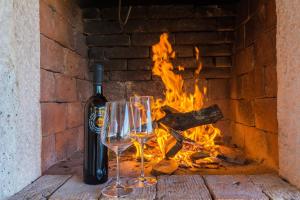 a bottle of wine and wine glasses in front of a fire at Holiday Home Irena-Adriatic Luxury Villas in Žman