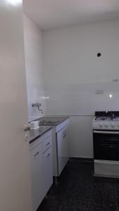 cocina blanca con fregadero y fogones en Departamento en el centro de Mendoza en Mendoza