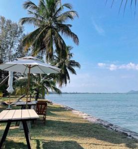 een strand met een tafel en een parasol en de oceaan bij Koh Yao Yai Sea Breeze House เกาะยาวใหญ่ซีบรีซเฮ้าส์ in Ko Yao Yai