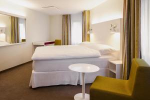 ein Hotelzimmer mit einem Bett und einem Stuhl in der Unterkunft Gästehaus by Stoos Hotels in Stoos