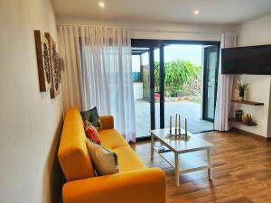 sala de estar con sofá amarillo y mesa en Villa Jardín Atteneri, en La Vegueta