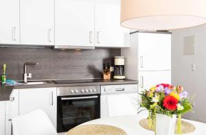 a kitchen with white cabinets and a table with a vase of flowers at K05 Fischerkaten LENI max 3 Pers in Dorf Körkwitz