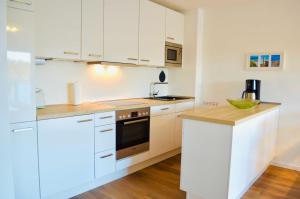 eine Küche mit weißen Schränken und einer Arbeitsplatte in der Unterkunft Buhne 10 App Nr 26 max 2 Pers in Dierhagen