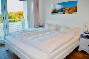 a white bed in a room with a large window at Buhne 10 App Nr 26 max 2 Pers in Dierhagen