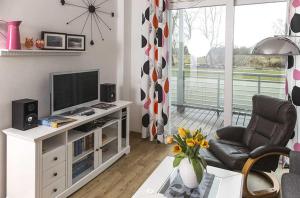sala de estar con TV, sofá y silla en DUENENROSE App Nr 03 max 3 Pers, en Dierhagen