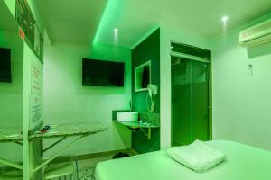 a green room with a bed and a tv at Motel Kaskata in Santa Cruz do Sul