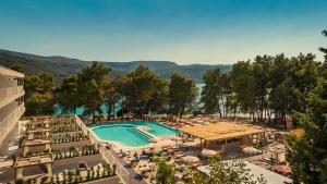 uma vista para um resort com uma piscina, mesas e cadeiras em HVAR PLACES HOTEL by Valamar em Stari Grad