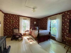 a bedroom with a bed and a chair and windows at Sewall House Yoga Retreat in Island Falls