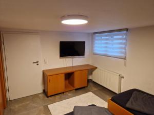 Habitación con TV en la pared y escritorio. en Monteurzimmer-mit GemeinschaftsBad und Küche BEI RASTATT en Muggensturm