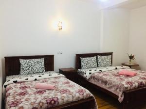1 dormitorio con 2 camas y una cruz en la pared en Highest Village Bungalow, en Nuwara Eliya