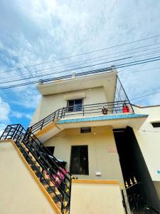 ein weißes Gebäude mit einem Balkon und einer Treppe darauf in der Unterkunft Sanjay Homestay New Hampi in Hampi