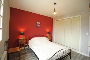 Un dormitorio con una pared roja y una cama en Plaisance, en Bujaleuf