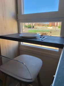 a table with a plate and a chair in front of a window at Apartamento ZAPILLO IRIA 1 in Almería