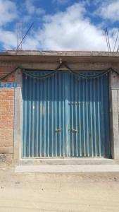 a blue metal door on the side of a building at LÍZU Tu casa en un pueblo zapoteca in Teotitlán del Valle