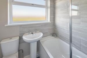 a white bathroom with a sink and a toilet and a window at Host & Stay - Armitage Road in Redcar